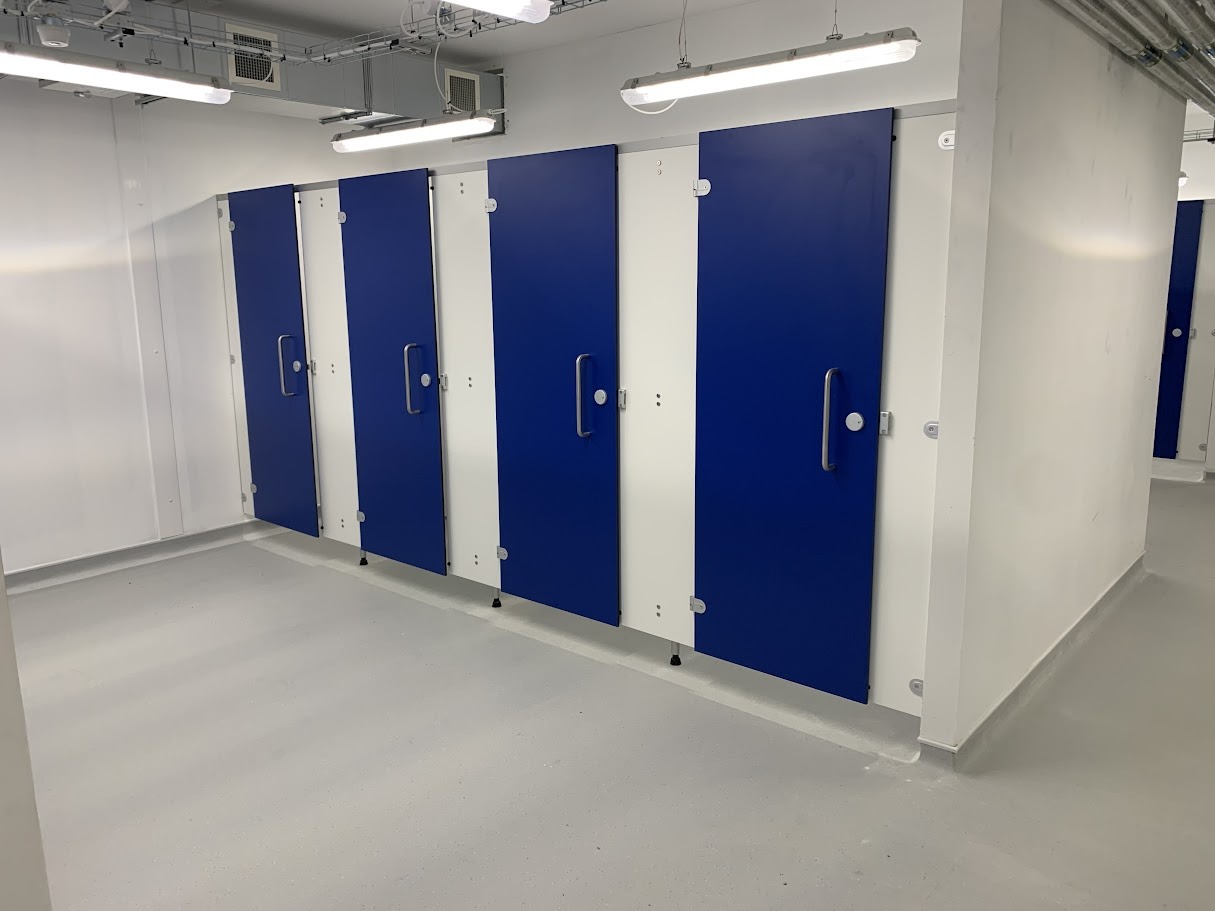 Blue solid grade laminate toilet cubicles against a white washroom wall