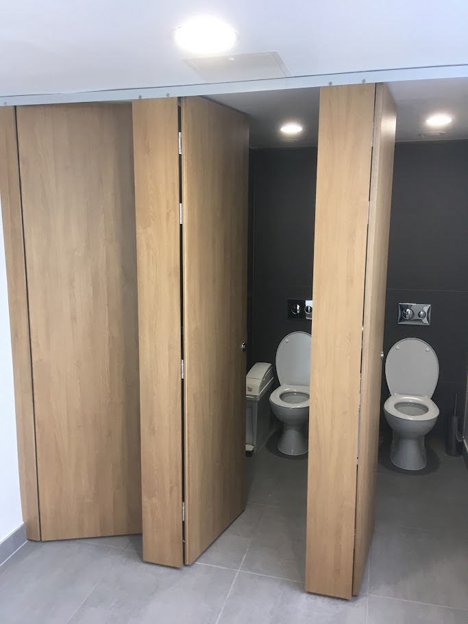 Woodgrain toilet cubicles with doors open onto WC compartments