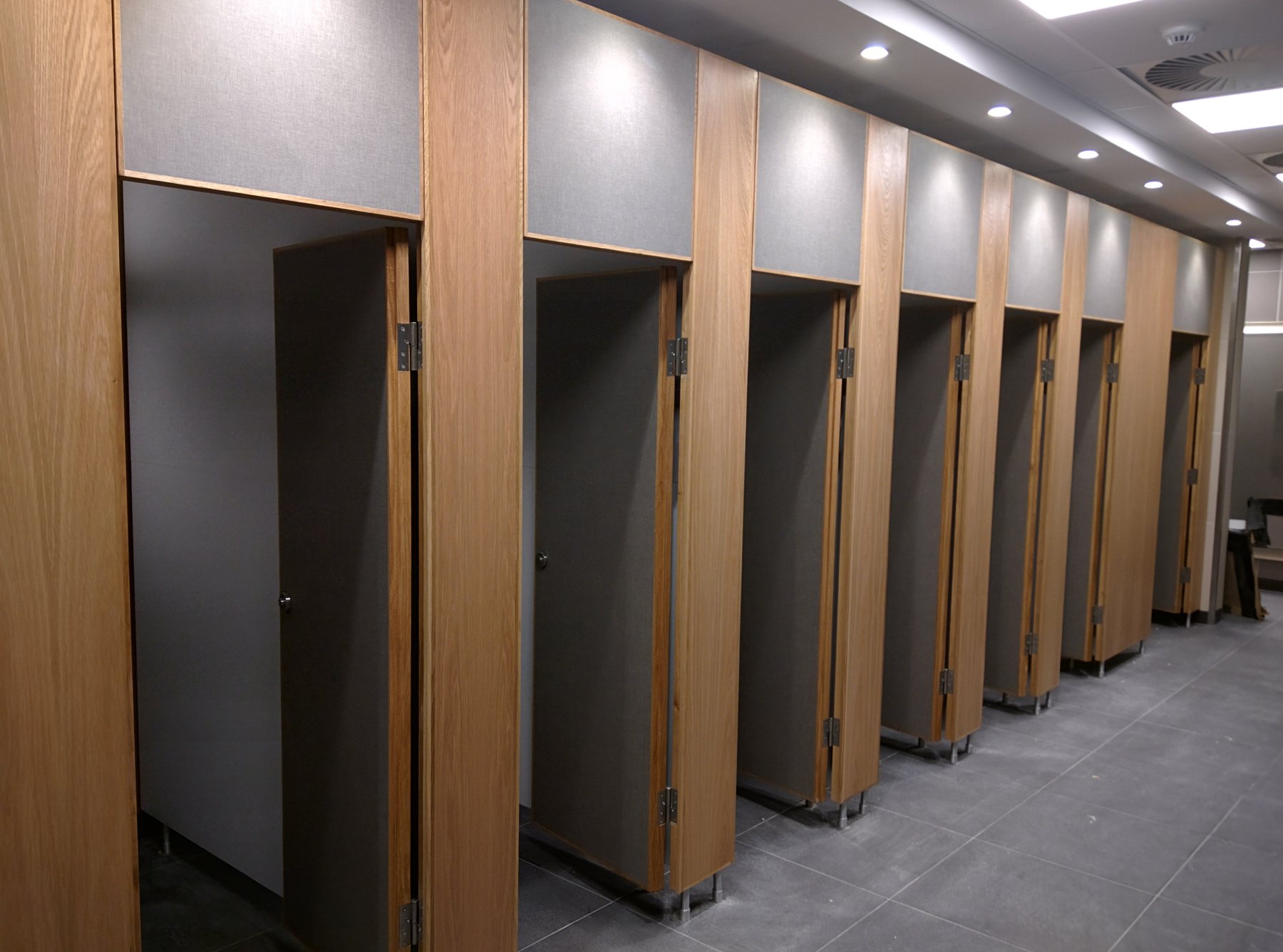 A run of solid grade laminate toilet cubicles in a commercial washroom